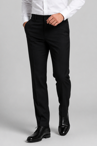 A person wearing slim black clergy pants with a white dress shirt and black dress shoes, standing against a light gray studio background.