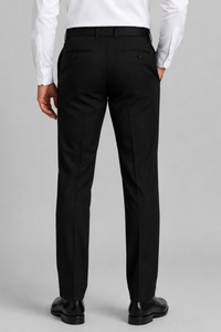 Rear view of a man wearing black dress pants with a white dress shirt and black dress shoes, standing against a light gray studio background.